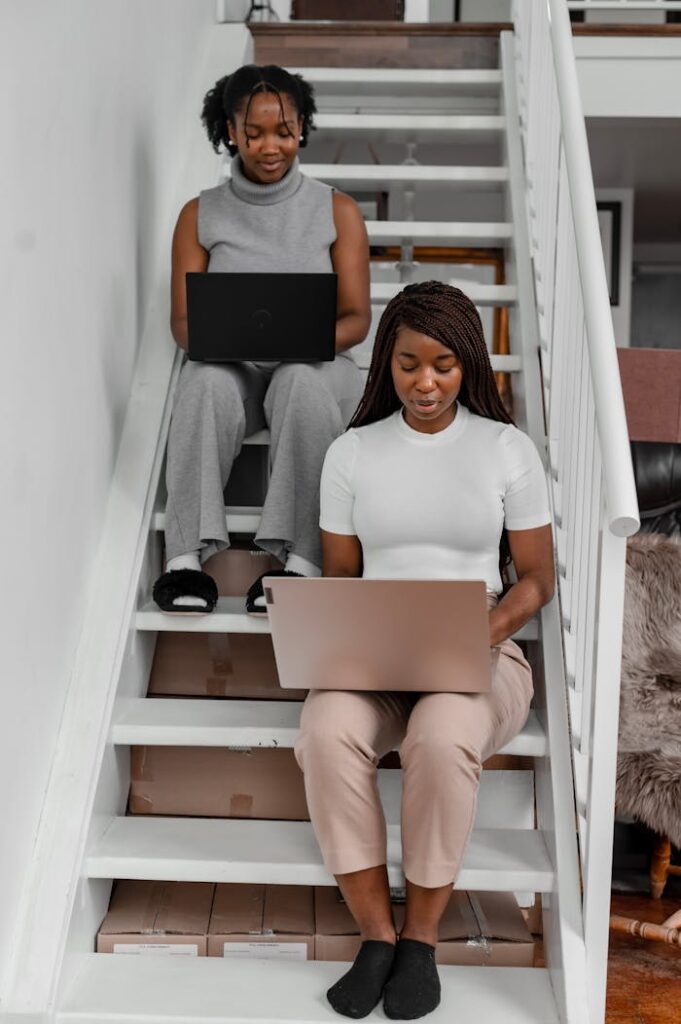 Women Using Their Laptop while Sitting on Stairs